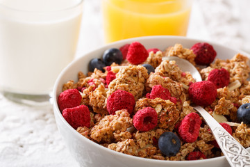 Healthy breakfast: granola with raspberries and blueberries, milk and juice close-up. horizontal