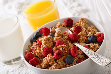 Granola with raspberries and blueberries, milk and orange juice close-up. horizontal
