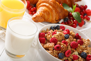 Baked granola with berries, as well as croissants, milk and juice close-up. horizontal