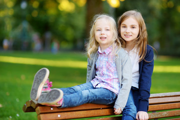 Two adorable little sisters laughing and hugging on summer day in a park © MNStudio