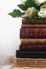 Old books with white flowers on romantic lace background close up