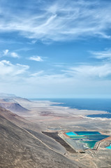 Obraz premium Vertical aerial view to industrial colorful pools, desert mountains and ocean