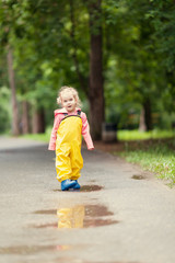 Fototapeta premium Small happy girl is walking in waterproof jumpsuit