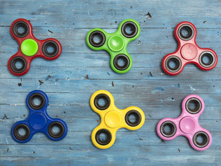 Fidget spinner toys on a blue wooden background. 