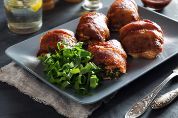 Stuffed chicken breasts rolled in bacon on grey tray