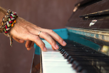 The hands of a young man playing piano on a street of city.