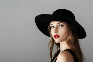 Beautiful sexy woman with red lipstick in black hat