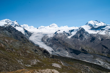 Panorama of snowy mountains with glacier in Swiss Alps.