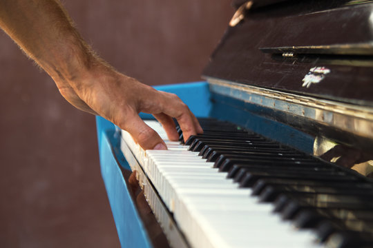 A hand of a young man playing piano on a street of city, closeup.