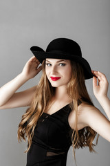 Fototapeta na wymiar Beautiful sexy woman with red lipstick in black hat