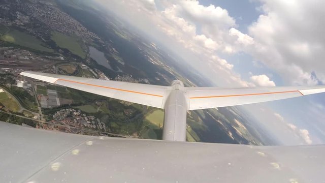 Glider flight over urban landscape. Footage from action camera placed on aircraft elevator. Soaring under clouds. 