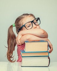 beautiful cute little sulky girl leaning on thick books