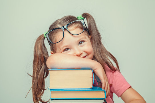 smiling beautiful cute little girl leaning on thick books