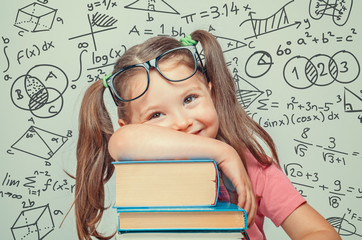 beautiful cute little genius girl with books. Math formulas, problems around her