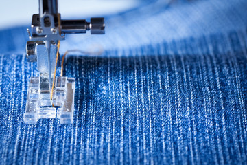 Foot Of Sewing Machine With Needle And Yellow Thread Sewing Fabric Of Denim Close Up.