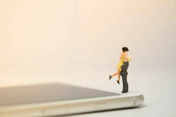 Miniature couple standing on smart phone,Online dating  ,Social live concept .copy space