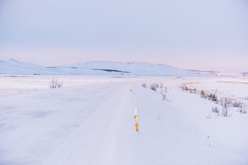 Morning winter drive in the Icelandic mountains by the snowy road