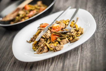 Plate with chicken meat and vegetable on wooden table.