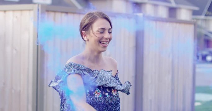 young woman in flowy dress dances with blue smoke bomb - slow motion