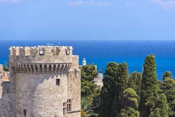 Impressive gothic castle from the medieval times, against deep blue sea and lush vegetation. Palace of the Grand Master of the Knights of Rhodes (Kastello), Rhodes island