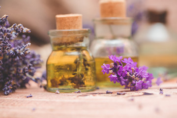 Lavender oil with fresh flowers on wooden background.