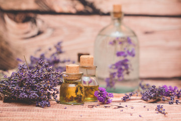 Fototapeta na wymiar Lavender oil with fresh flowers on wooden background.
