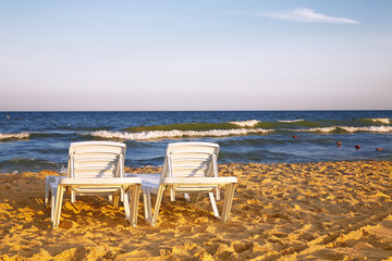 Fototapeta na wymiar Two deckchairs on the sandy beach