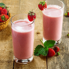 Fresh strawberry milkshake on a wooden table. Healthy fruit smoothie drink.