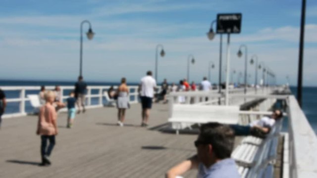 Blurred people walking on a pier on a sunny day