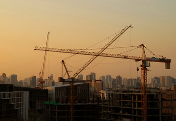 Construction cranes keep moving under the golden after sunset sky of Bangkok, Thailand
