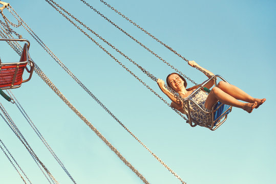 Young girl on a whirligig in amusement park.