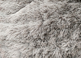 Fluffy texture fabric. Closeup of the pillow with gray fur cover. Abstract background.