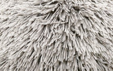 Fluffy texture fabric. Closeup of the pillow with gray fur cover. Abstract background.