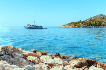 A rocky shore, boats and a ship.