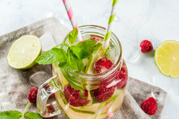 Summer drinks, cocktails. Vegan food. Infused detox water with lime, mint and fresh organic raspberries. On light concrete table, Copy space