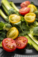 A beautiful vegetable salad on a dark plate. Graphic still life.
