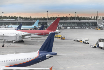 Airplane near the terminal in an airport at the sunset