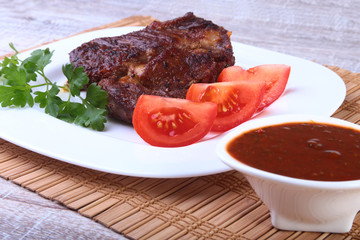 Grilled beef steak with tomato, and hot asian chillies garlic sauce on plate on wooden background.