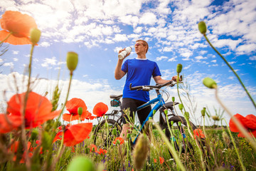 Young bicyclist rides on poppy field