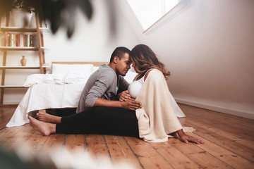 Romantic pregnant couple sitting on the floor
