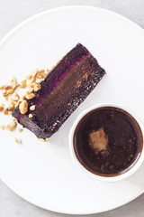 Hot coffee and slice of fudgy raw chocolate mousse cake on white plate. Vegan gluten, dairy free dessert