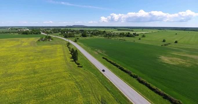 The European route E 20 passing through yellow and green pastures of Estonia country. Road from Narva to Tallinn. Aerial view