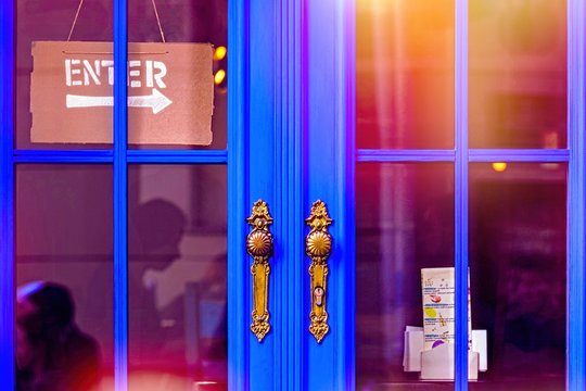 Enter signt on blue doors with bronze handle. Modern classic exterior design. Sunlight reflection