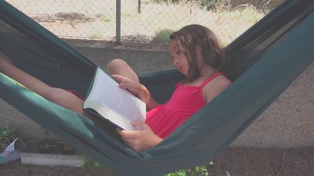 Ni&ntilde;a leyendo pl&aacute;cidamente en hamaca