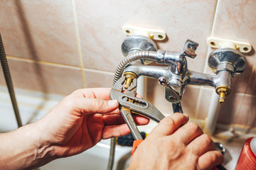 Man repair and fixing leaky old faucet in bathroom - 162436963