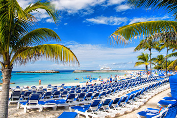 Rows of blue chairs on sunny beach with white sand