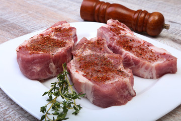 Raw pork chops and spice grinder on cutting board. Ready for cooking.