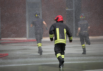 Firefighters run fast under the splashes of water