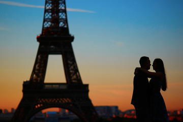 Silhouettes of couple at sunrise or sunset in front of the Eiffel tower
