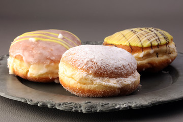 German donuts - berliner with jam and icing sugar in a tray on a grey background.